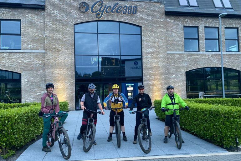 Group of mountain bikers riding eMTBs together on a forest trail, wearing helmets and cycling gear, representing Cycle 360 and Enduro Isle’s upcoming social eMTB ride.